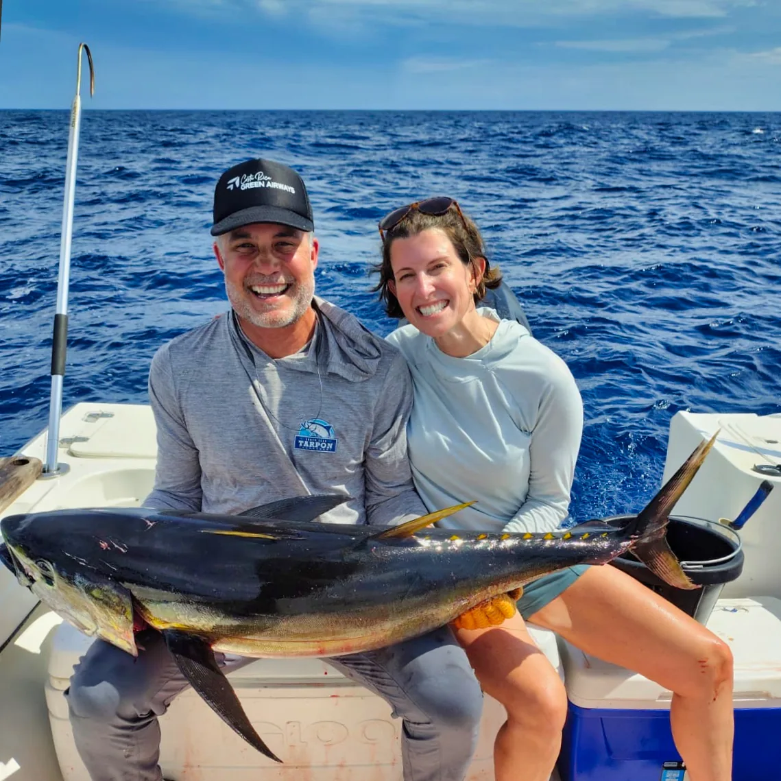 Couple with a yellowfin tuna on an inshore charter from Playa Garza A couple holds a large yellowfin tuna across the gunwale in deep blue water off Nosara.