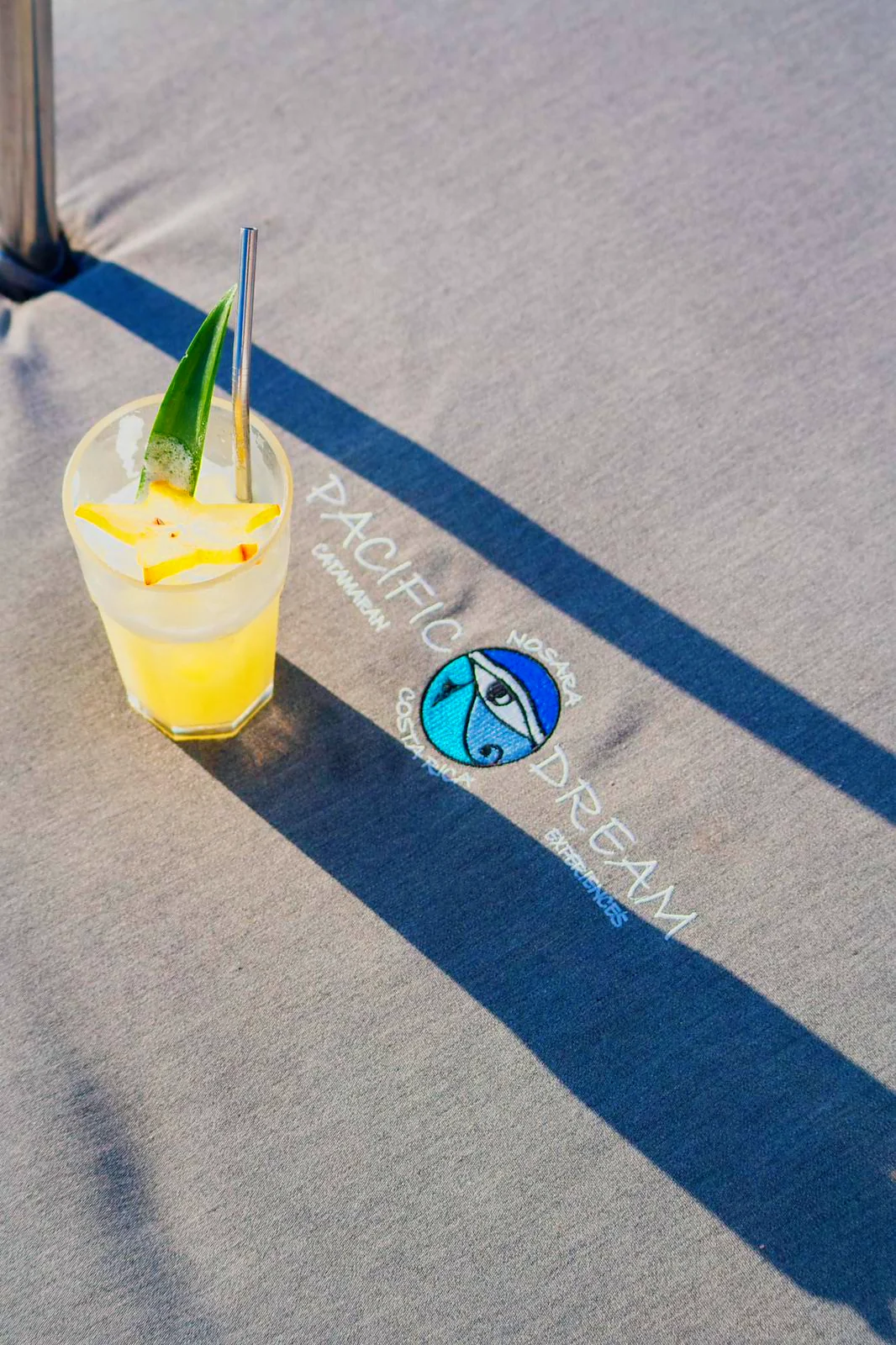Cocktail on a Pacific Dream cushion | Pacific Dream Nosara A fresh pineapple cocktail on a deck cushion embroidered with the Pacific Dream logo.